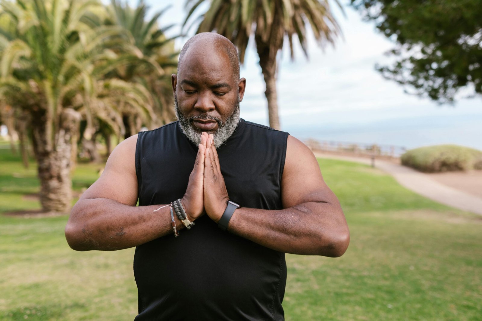 Man practicing yoga outdoors, promoting relaxation and mindfulness in a serene park environment.